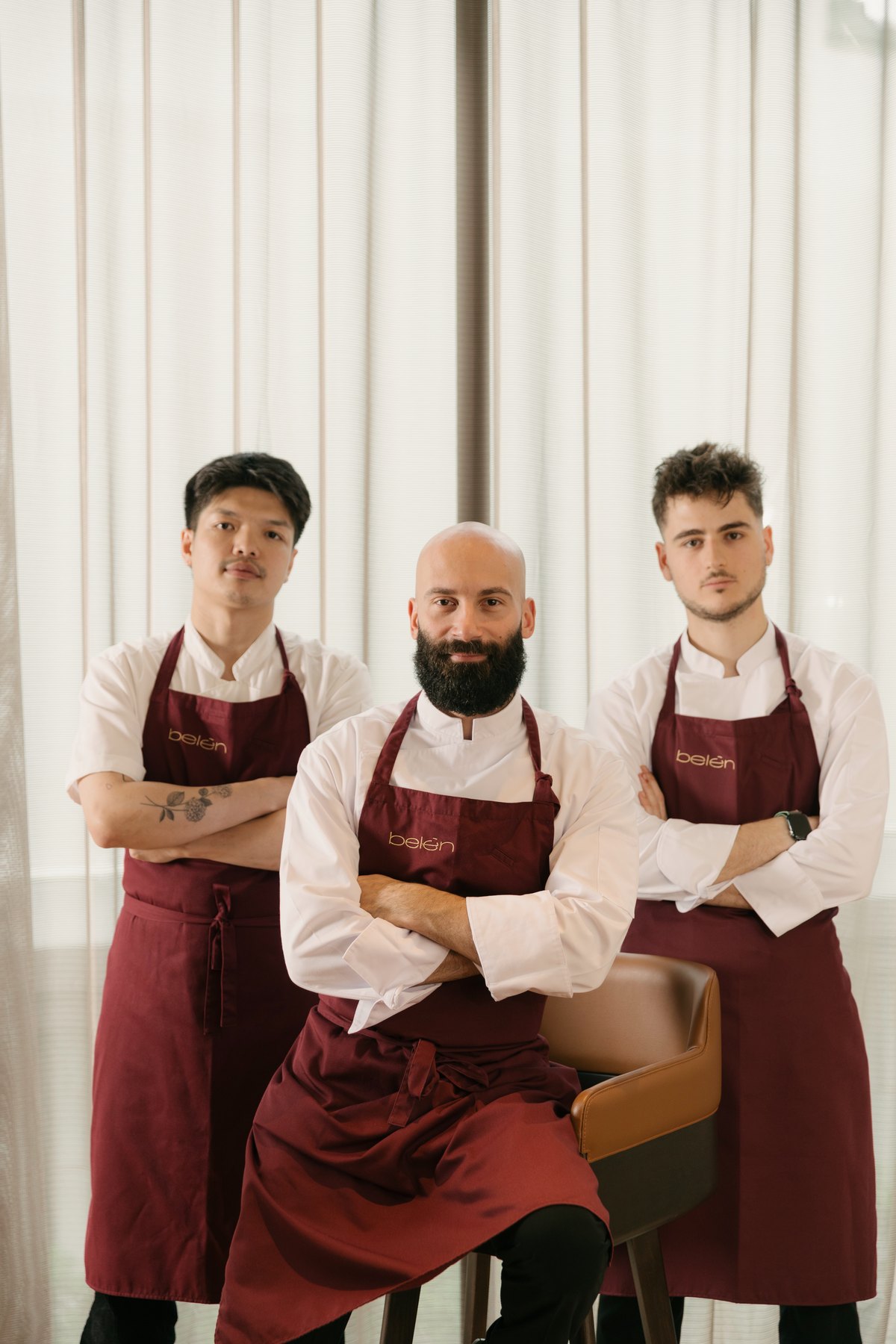 Head Chef Matteo with two of the Belén cooks, in burgundy Belén aprons, in front of the dining-room curtains