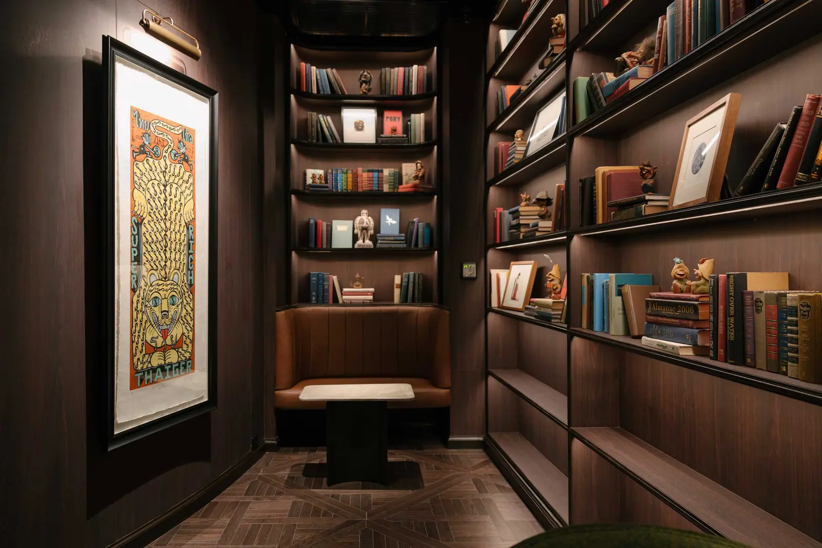 Library nook with a framed yellow tiger poster, book-filled shelves and a curved leather banquette
